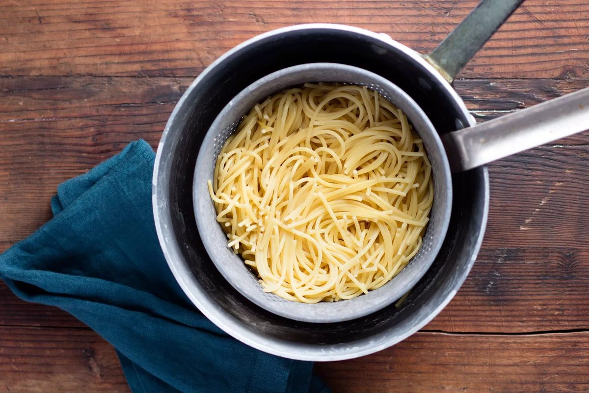 Bowl of al dente spaghetti with sauce on a simple kitchen table