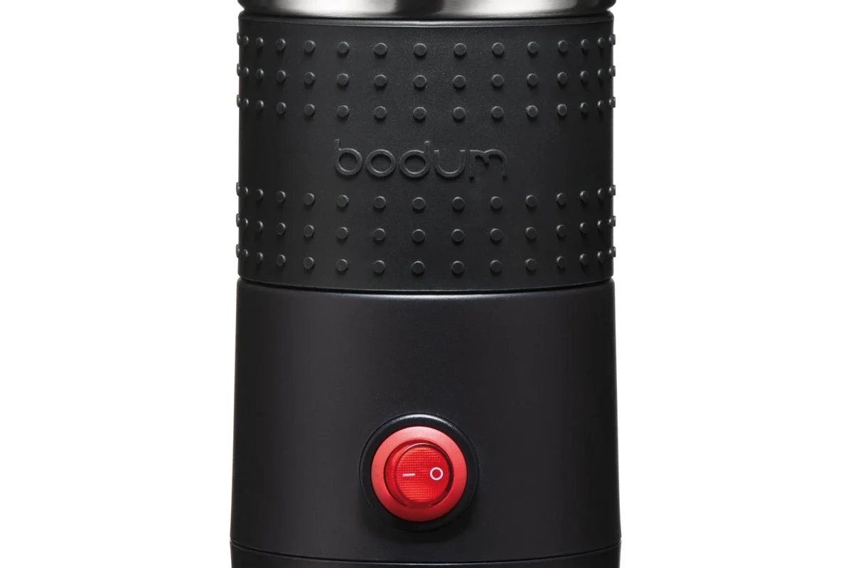 Bodum electric milk frother beside a cup of coffee with foamed milk in a kitchen