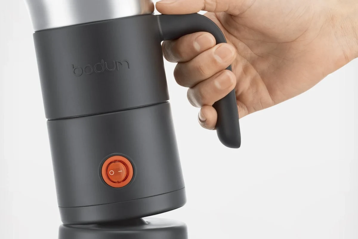 Bodum electric milk frother beside a cup of coffee with foamed milk in a kitchen