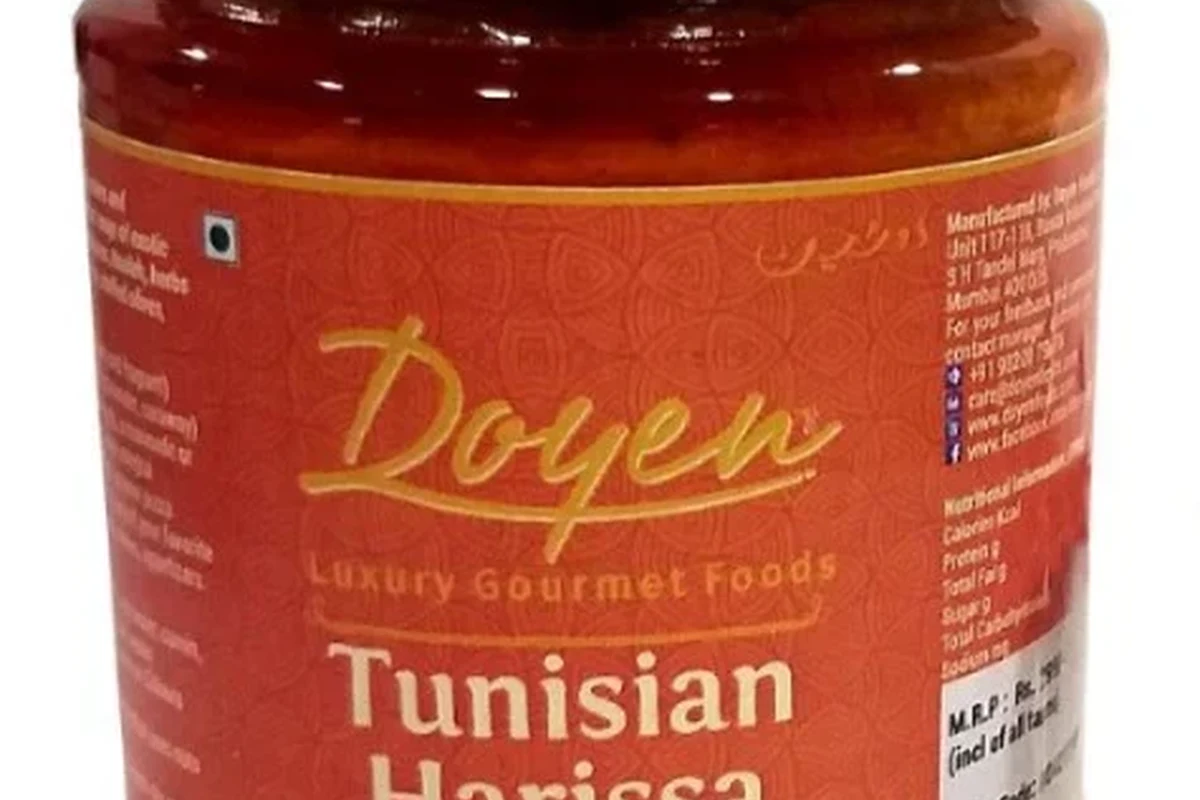 Jar of harissa paste with spices and pasta ingredients on a kitchen counter