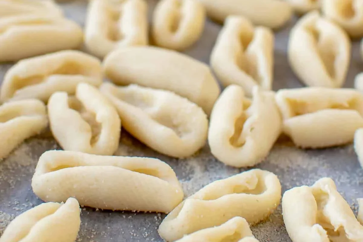 Bowl of cavatelli pasta with tomato sauce and herbs on a kitchen table