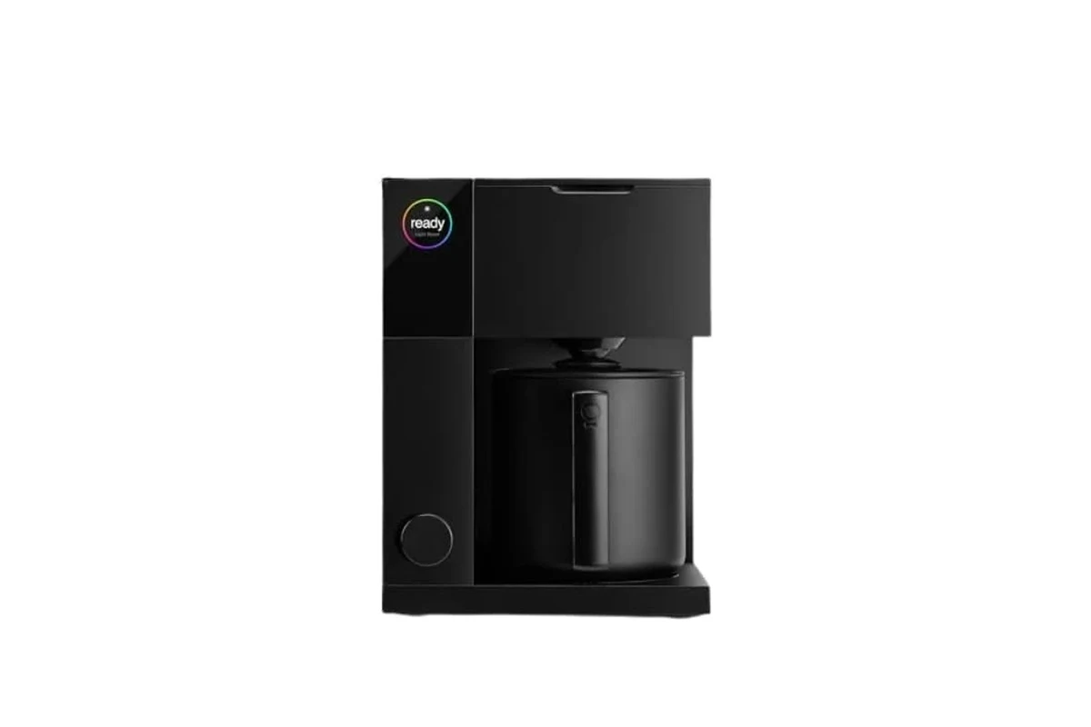 French press coffee maker with grounds, hot water, and a plunger on a kitchen counter