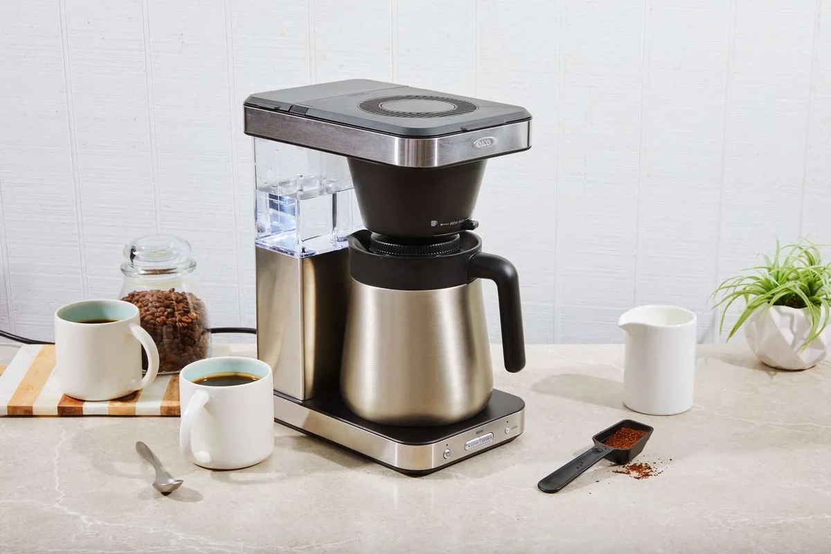 Cold brew coffee in a glass pitcher with coffee grounds and a kitchen counter setup