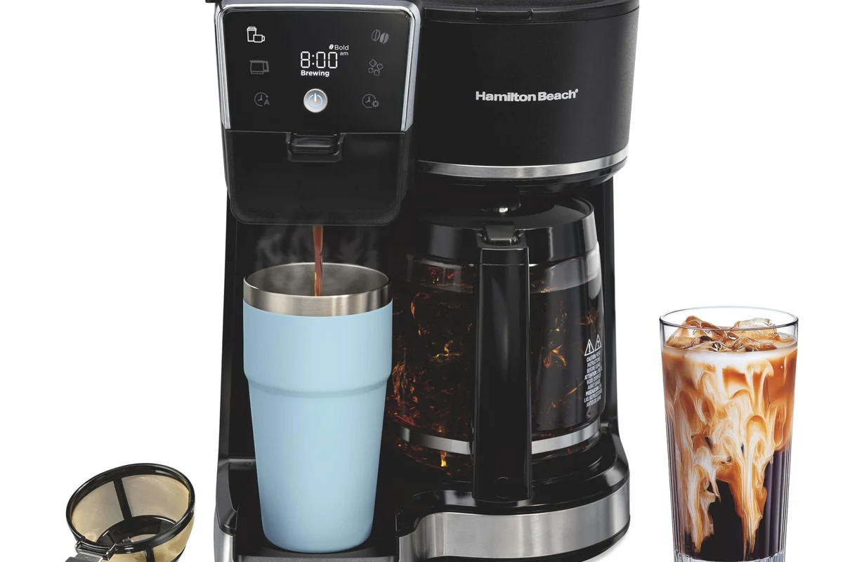 French press coffee maker with grounds, hot water, and plunger on a kitchen counter