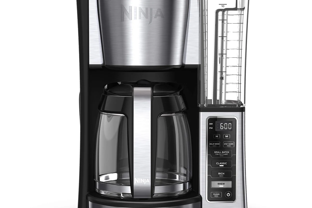 French press coffee maker on a kitchen counter with coffee grounds and hot water