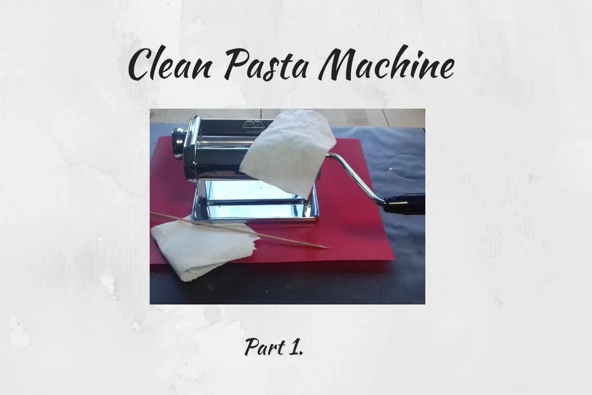 Hand cleaning a pasta machine with a brush and dry cloth on a kitchen counter