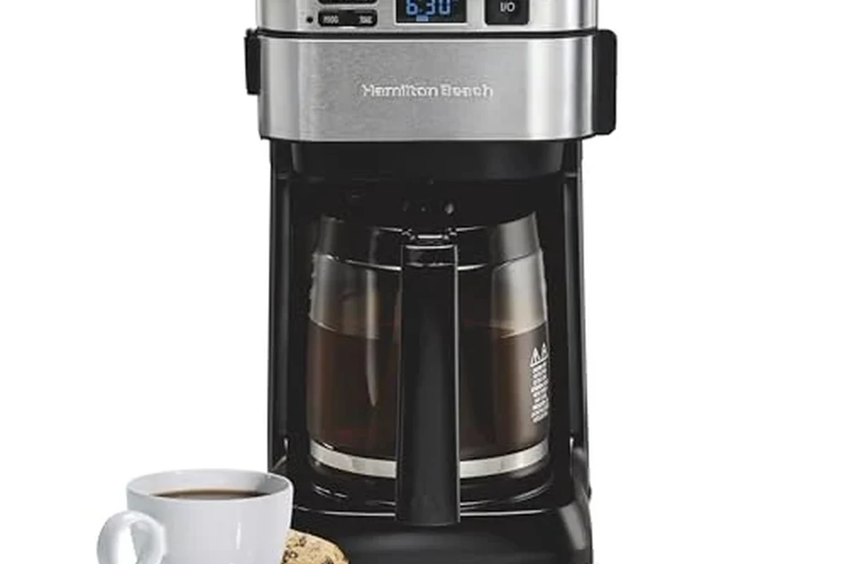 French press coffee in a glass press with coarse grounds and a mug on a kitchen counter