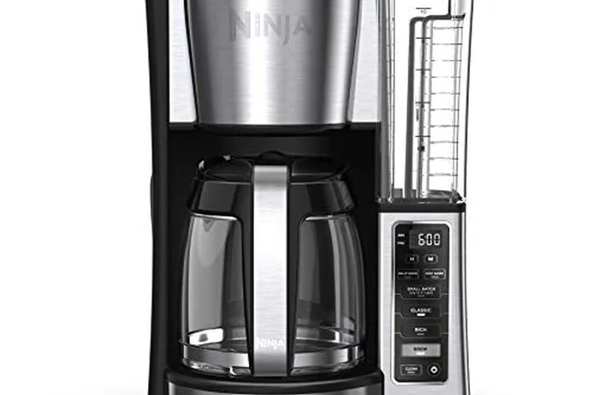 French press coffee maker with grounds, hot water, and a plunger on a kitchen counter