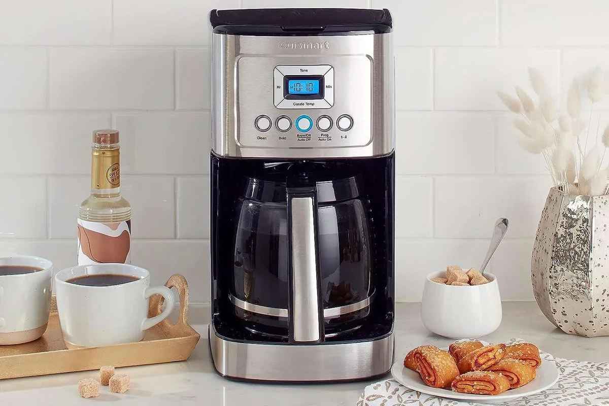 French press coffee maker with plunger, coffee grounds, and hot water on a kitchen counter