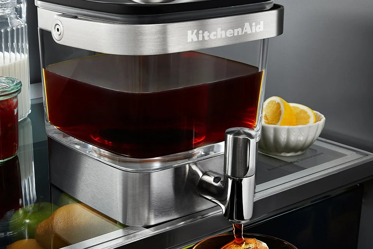 French press coffee maker with fresh grounds, hot water, and a plunger on a kitchen counter