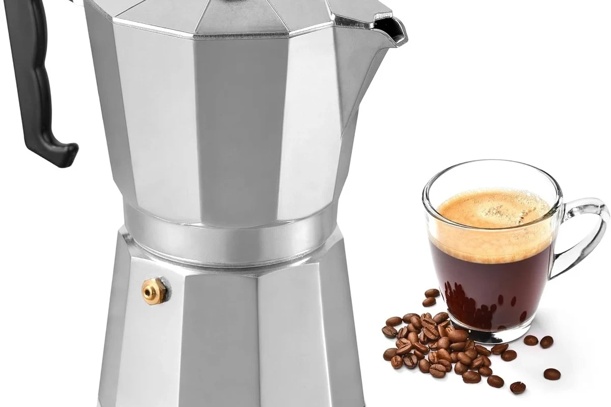 French press coffee maker with coarse coffee grounds and a grinder on a kitchen counter