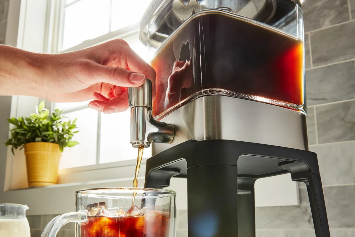 French press coffee maker with plunger, grounds, and brewed coffee on a kitchen counter