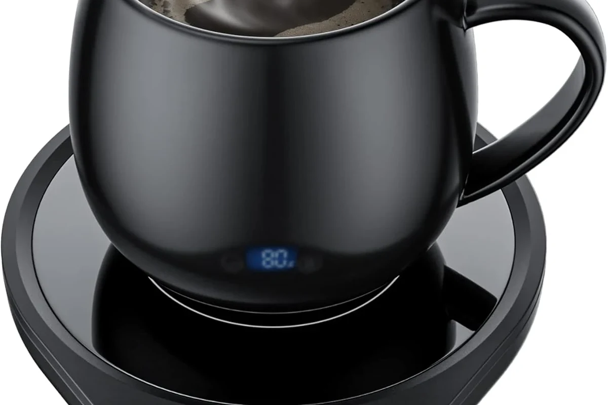 Coffee mug warmer on a kitchen counter beside a ceramic mug and a clean cloth