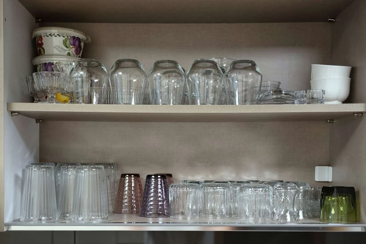 Coffee mugs stored upside down on a clean kitchen shelf in a cabinet