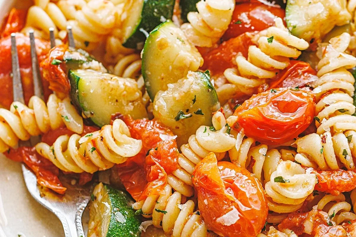 Zucchini noodles tossed with sauce in a skillet on a kitchen counter