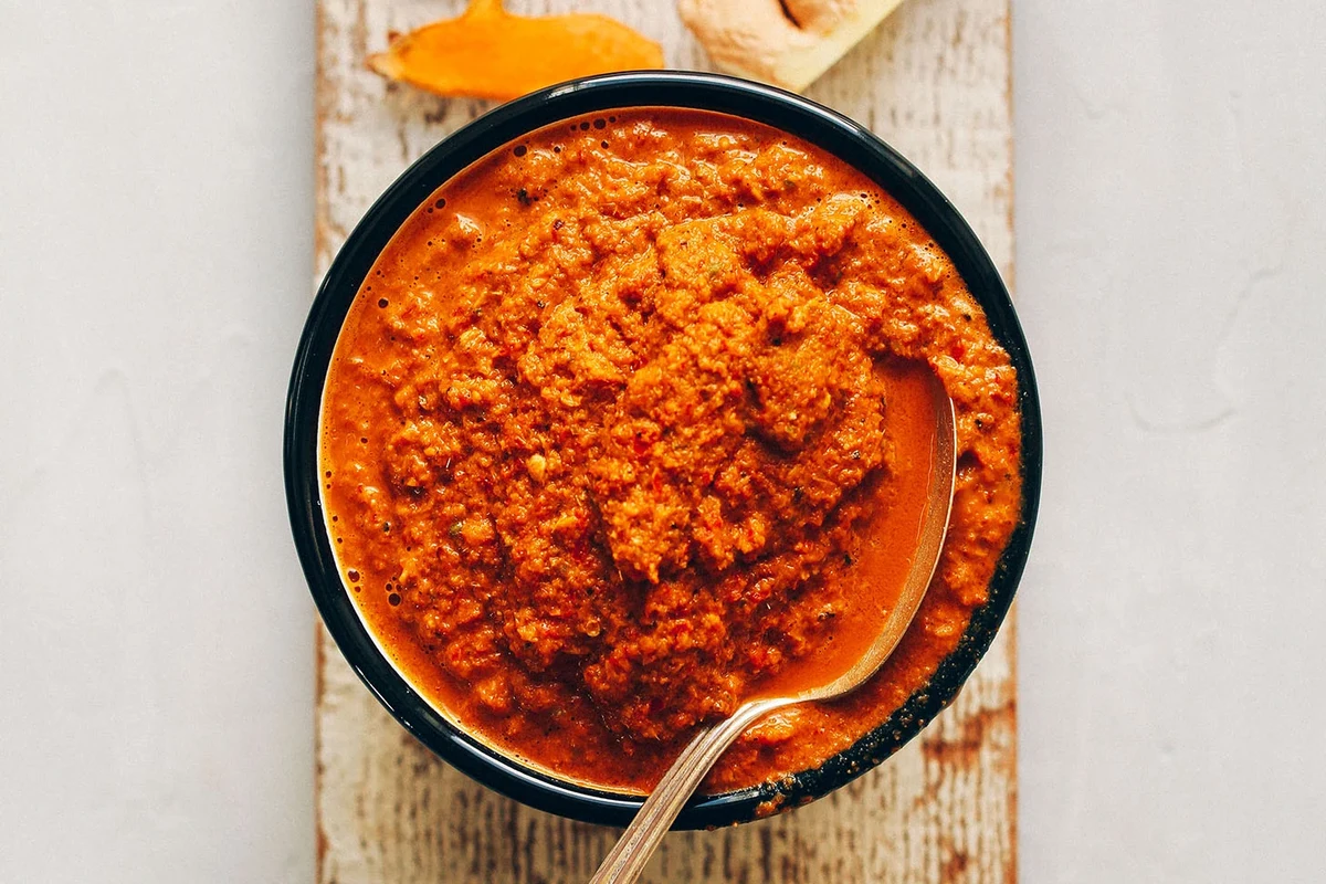 Bowl of curry paste cooking with oil, vegetables, rice, and pasta ingredients in a home kitchen