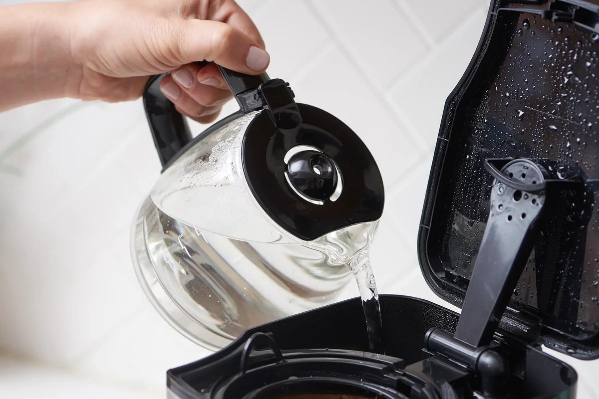 Air fryer basket, tray, and cleaning supplies arranged on a kitchen counter for deep cleaning