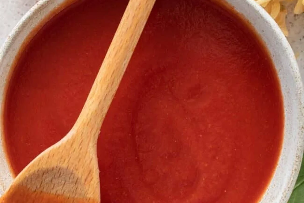 Tomato paste and tomato sauce in bowls on a kitchen counter with pasta ingredients