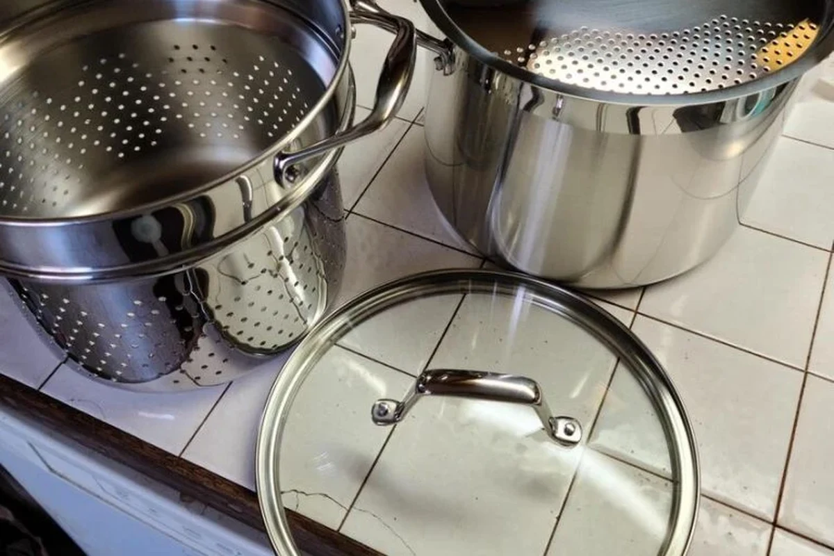 Person draining spaghetti into a colander in a clean home kitchen
