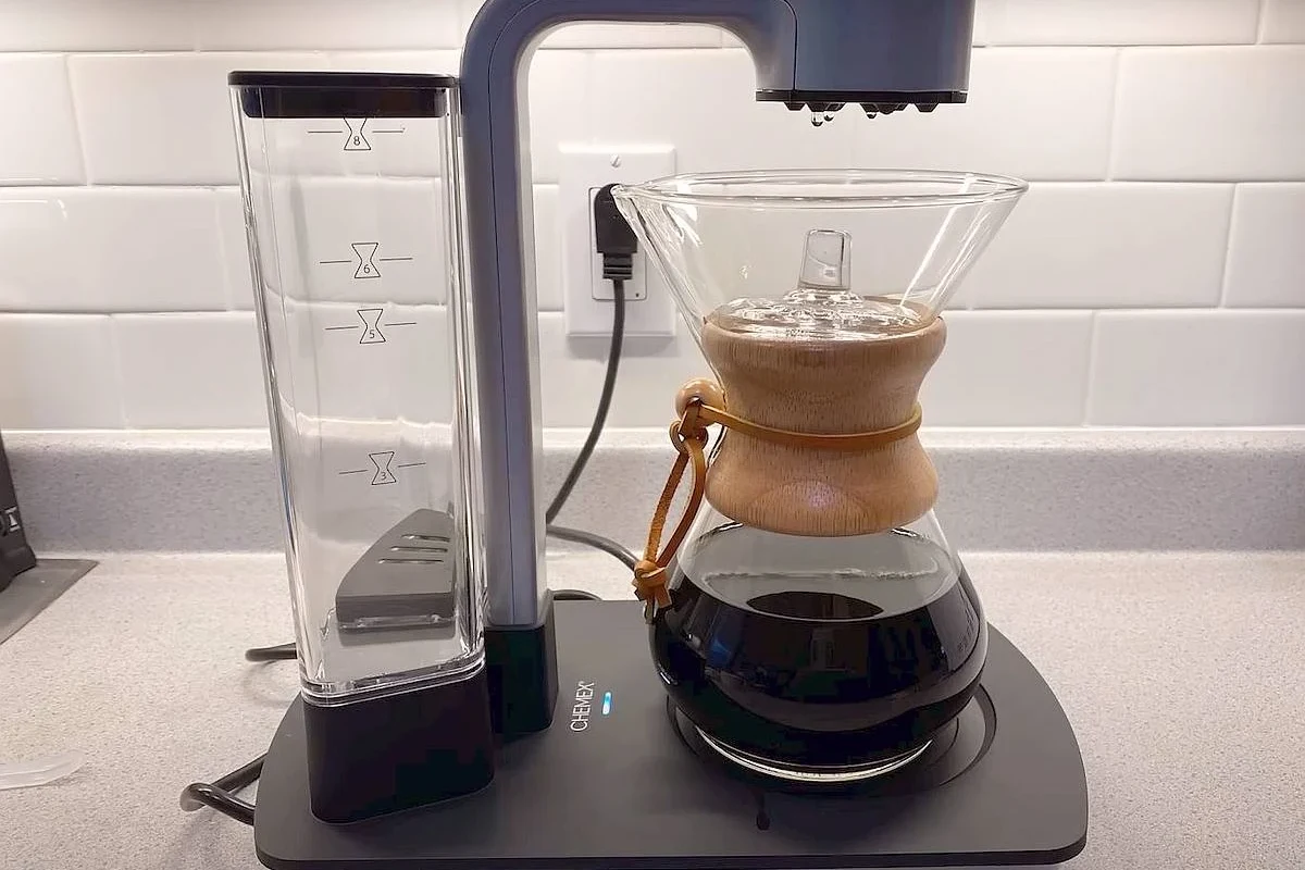 French press coffee brewing setup with coarse grounds, hot water, and a glass press on a kitchen counter