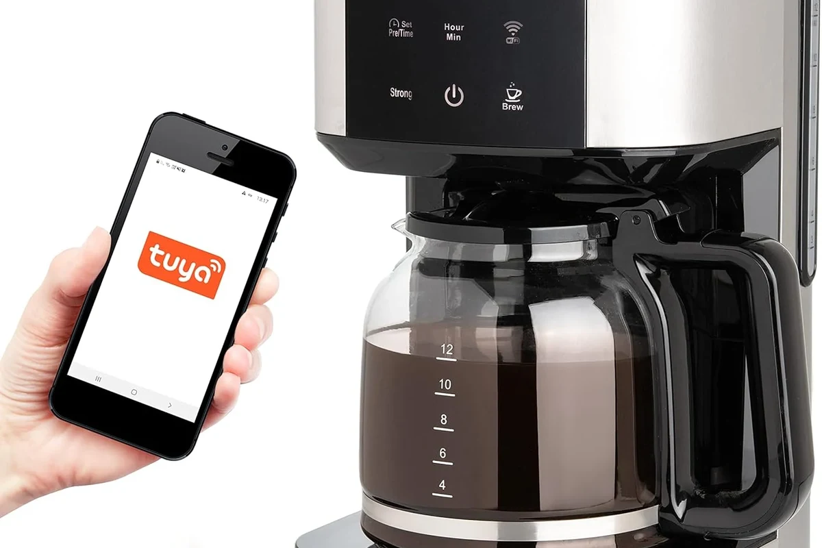 Glass pitcher of cold brew coffee beside espresso equipment on a kitchen counter