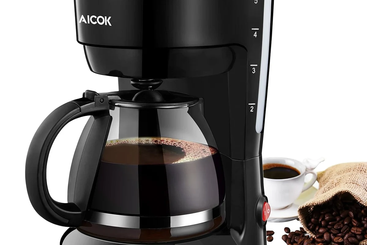 French press coffee maker with coarse grounds, hot water, and a fresh cup on a kitchen counter