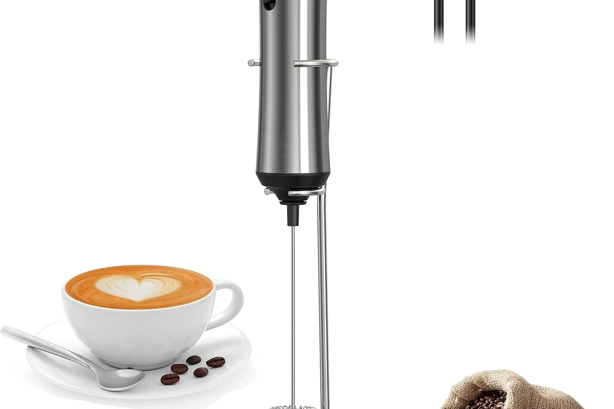 Electric milk frother making cappuccino foam beside a cup of espresso in a home kitchen