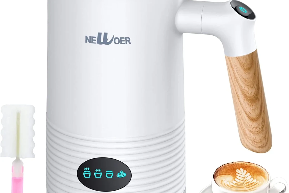 Electric milk frother making foamy milk beside a coffee cup on a kitchen counter