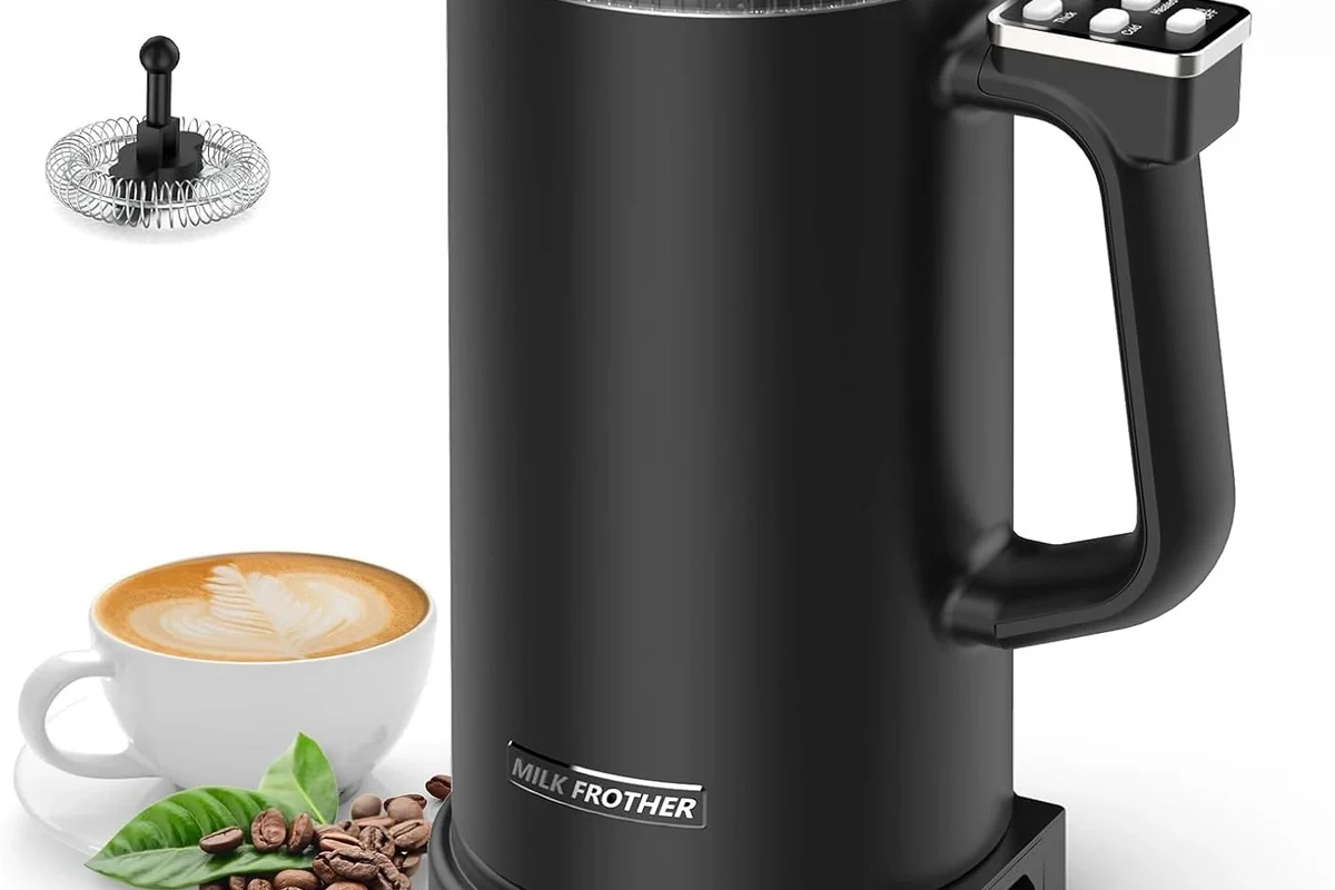 Electric milk frother making foam in a kitchen beside a coffee cup