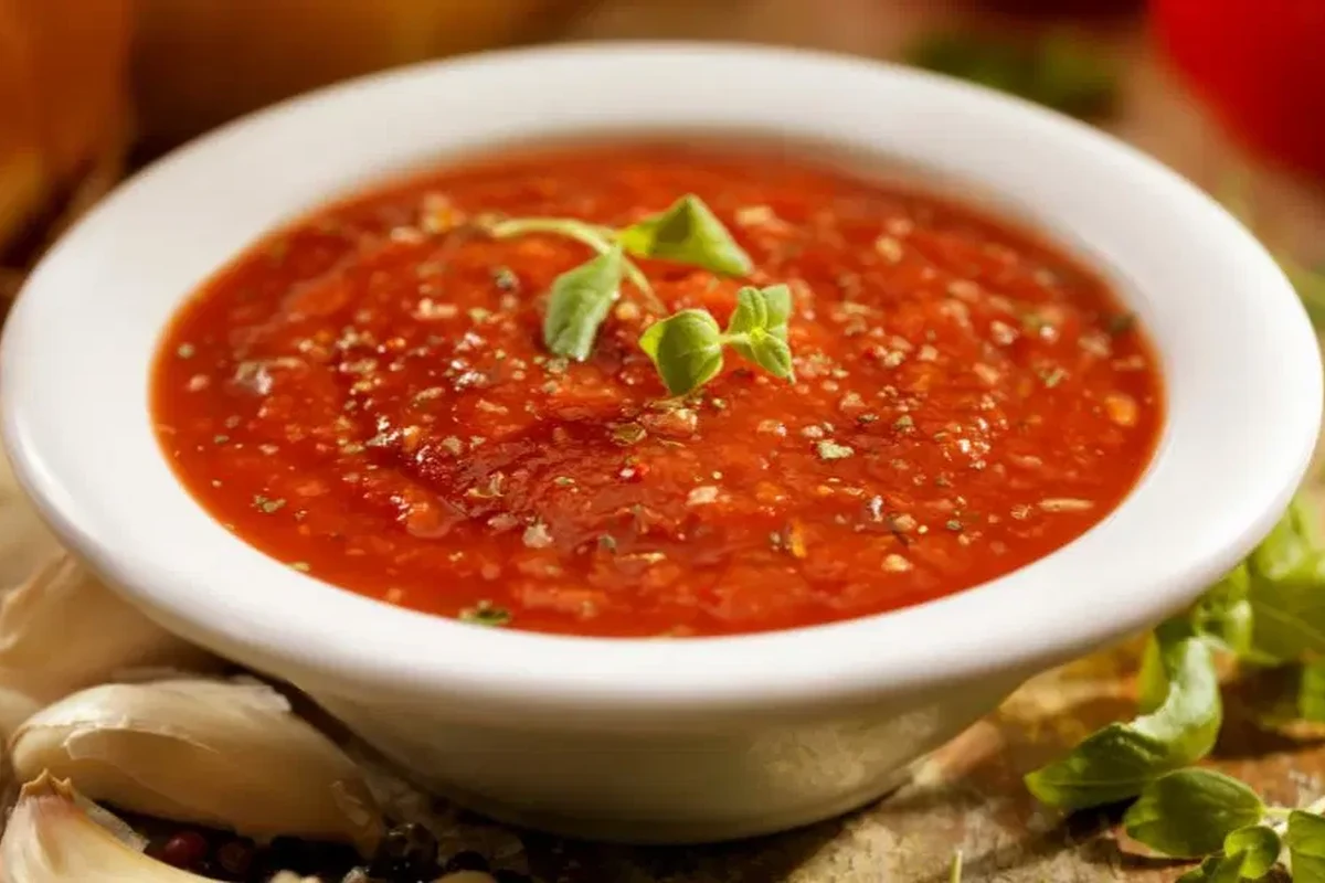 Jar of pasta sauce on a kitchen counter with a spoon and freshness check notes