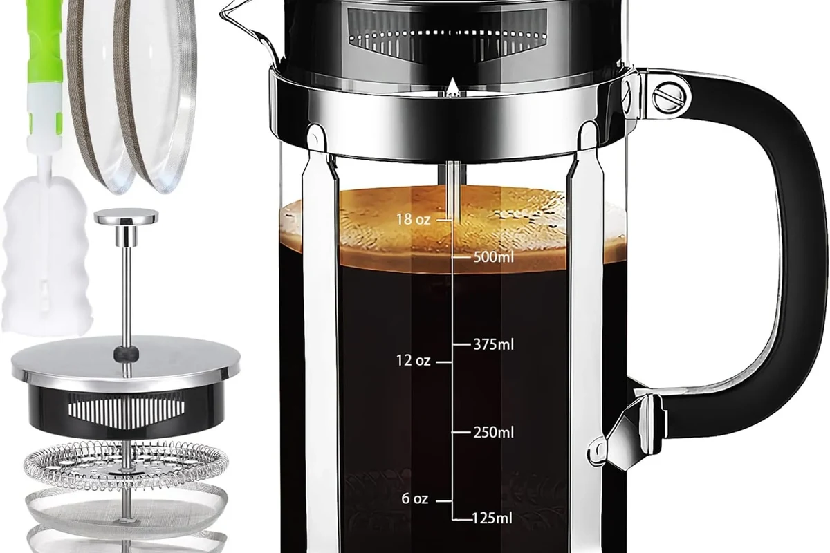 French press coffee maker with grounds, hot water, and plunger on a kitchen counter