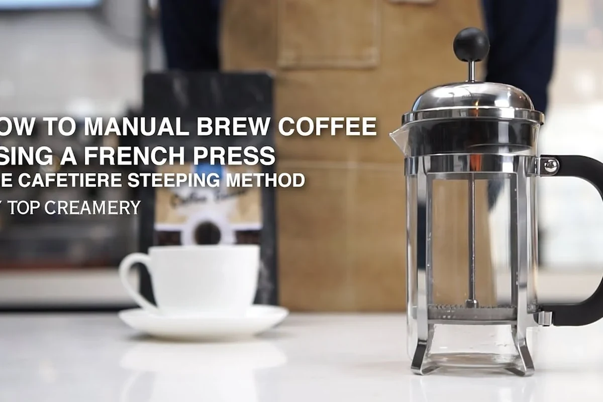 French press coffee maker with coarse grounds, hot water, and a hand pressing the plunger