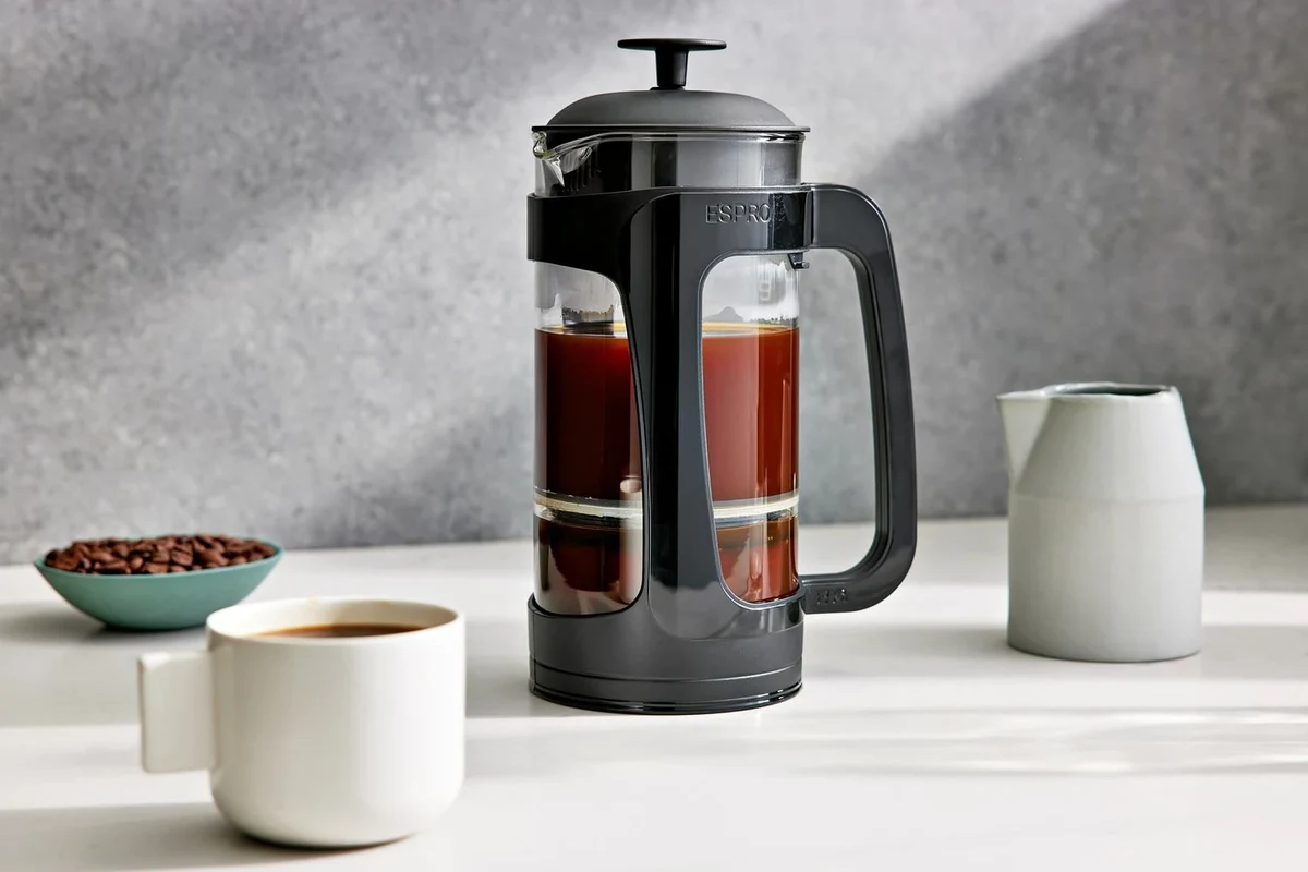 French press coffee brewing setup with coarse grounds, hot water, and a glass carafe