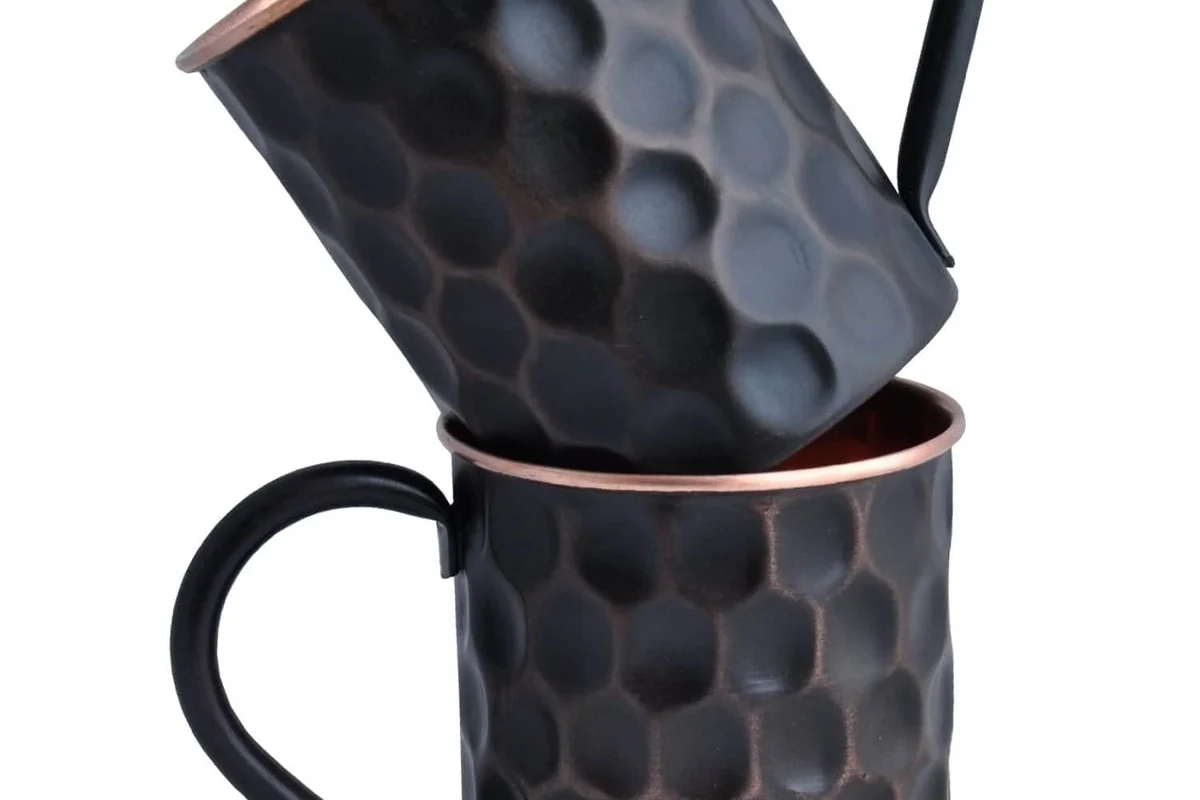 Copper mug with lined interior beside a hot cup of coffee on a kitchen counter