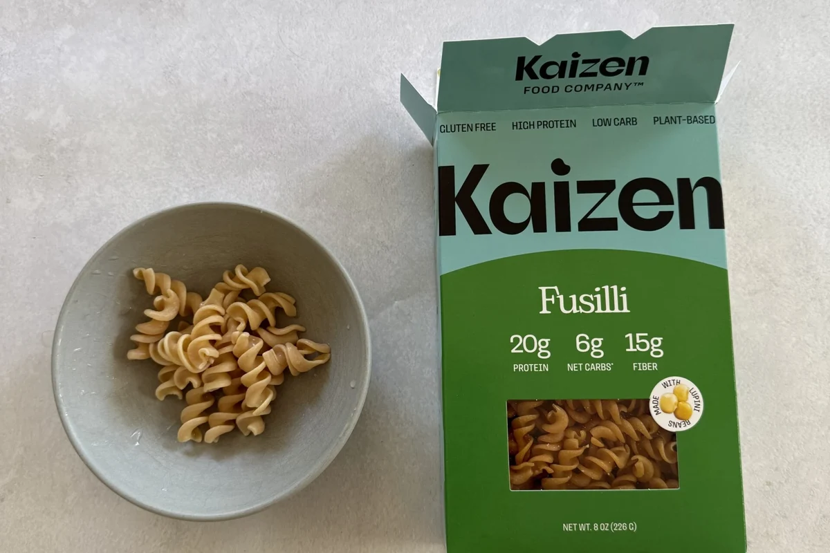 Bowl of Kaizen pasta with tomato sauce, vegetables, and grilled chicken in a bright kitchen