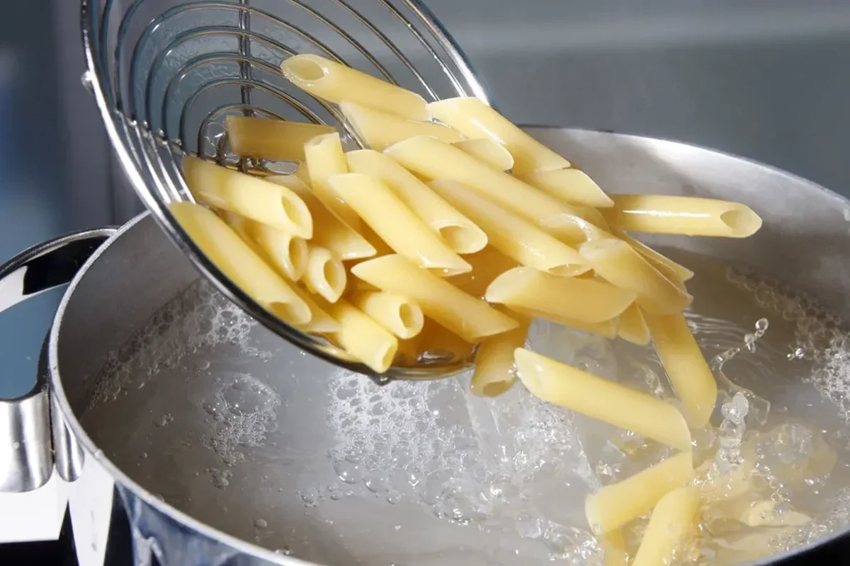 Pot of pasta being stirred in boiling water to prevent sticking
