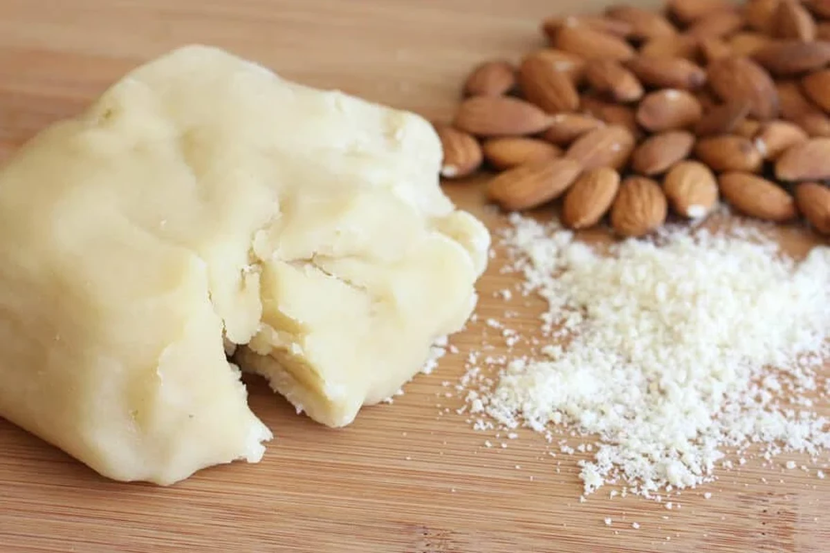 Homemade almond paste ingredients and a smooth paste in a kitchen bowl