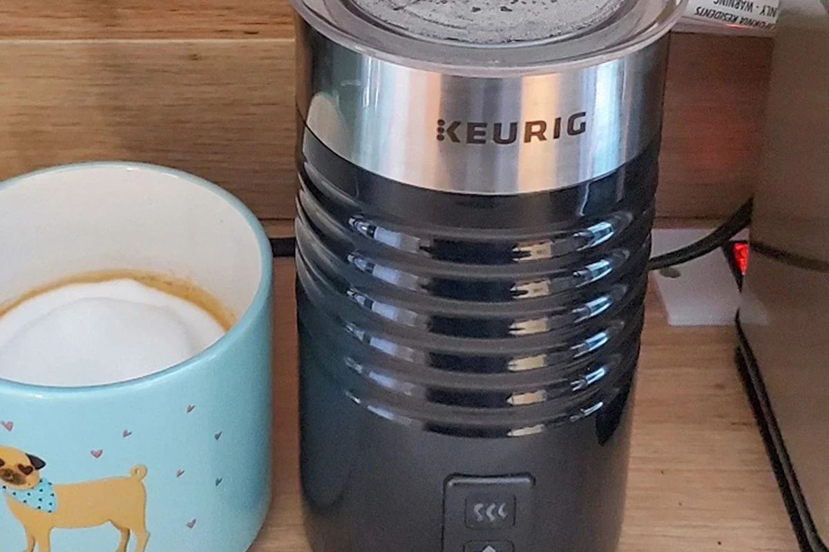 Electric milk frother making smooth cafe style foam in a kitchen mug