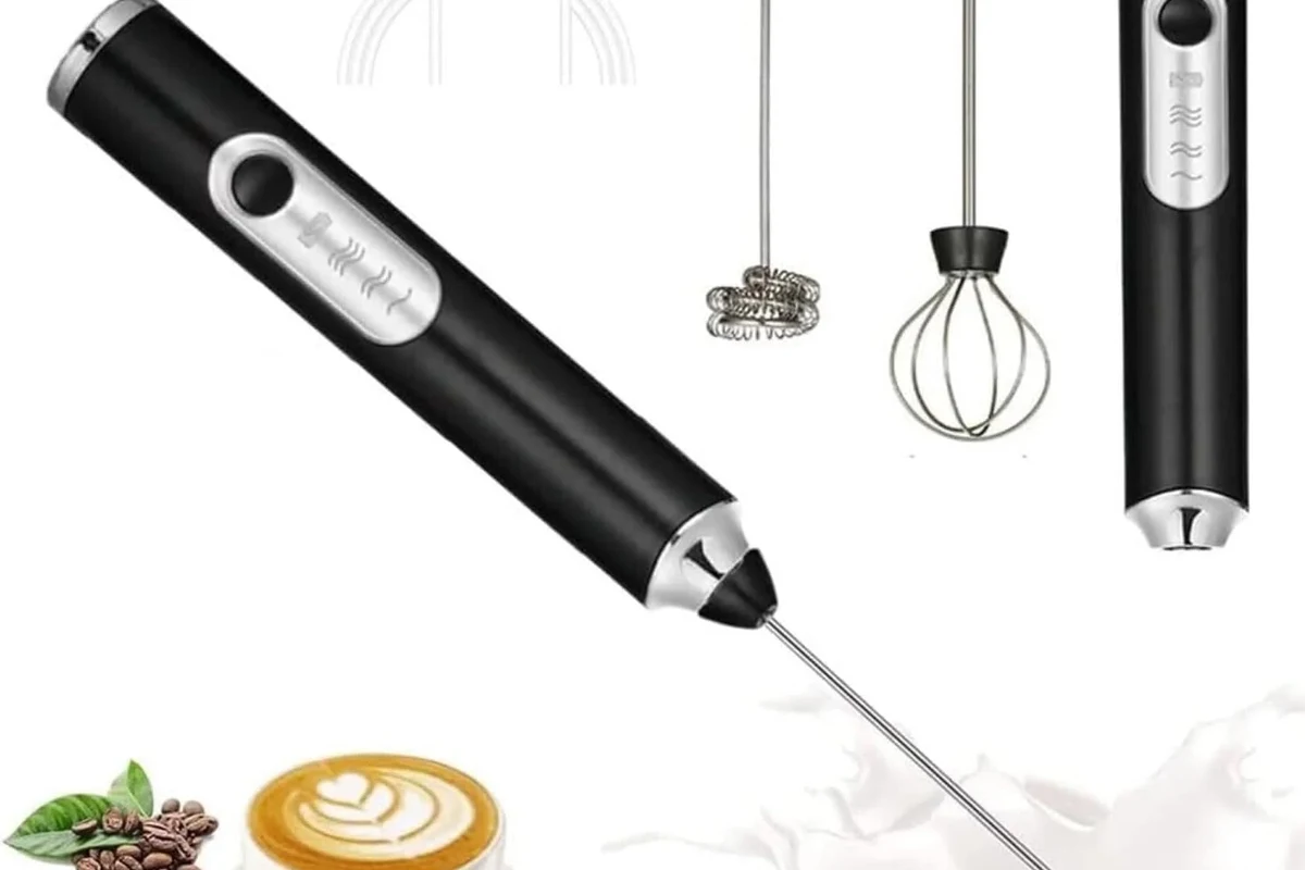 Electric milk frother making foamy milk beside a mug of homemade latte