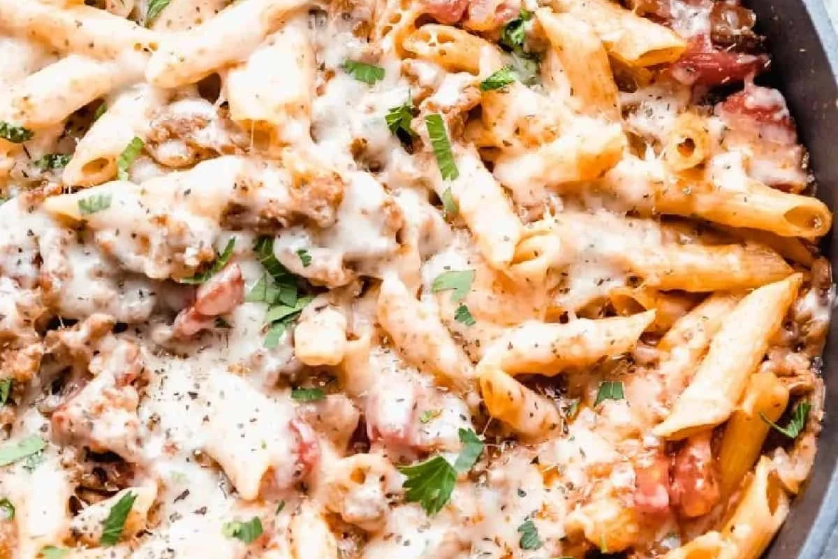 Pasta with Italian sausage in a skillet with tomato sauce and herbs