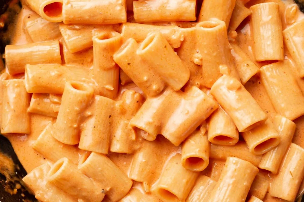 Creamy pink sauce pasta in a bowl with basil and Parmesan on a kitchen counter