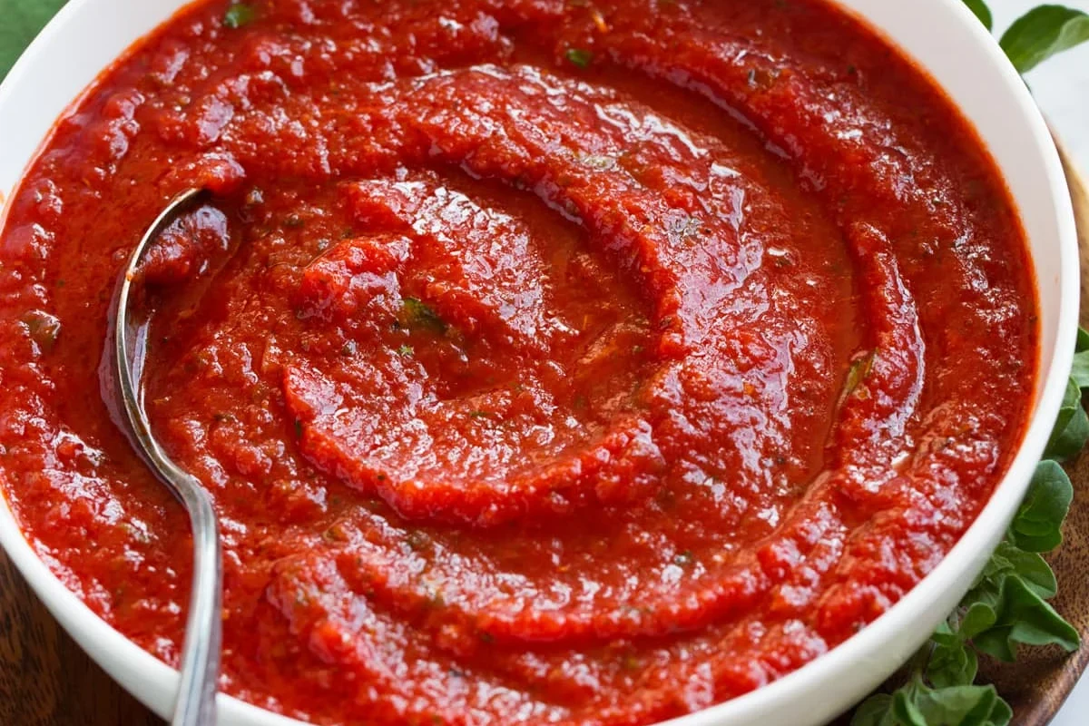 Bowl of homemade pizza sauce made from tomato paste with herbs and olive oil