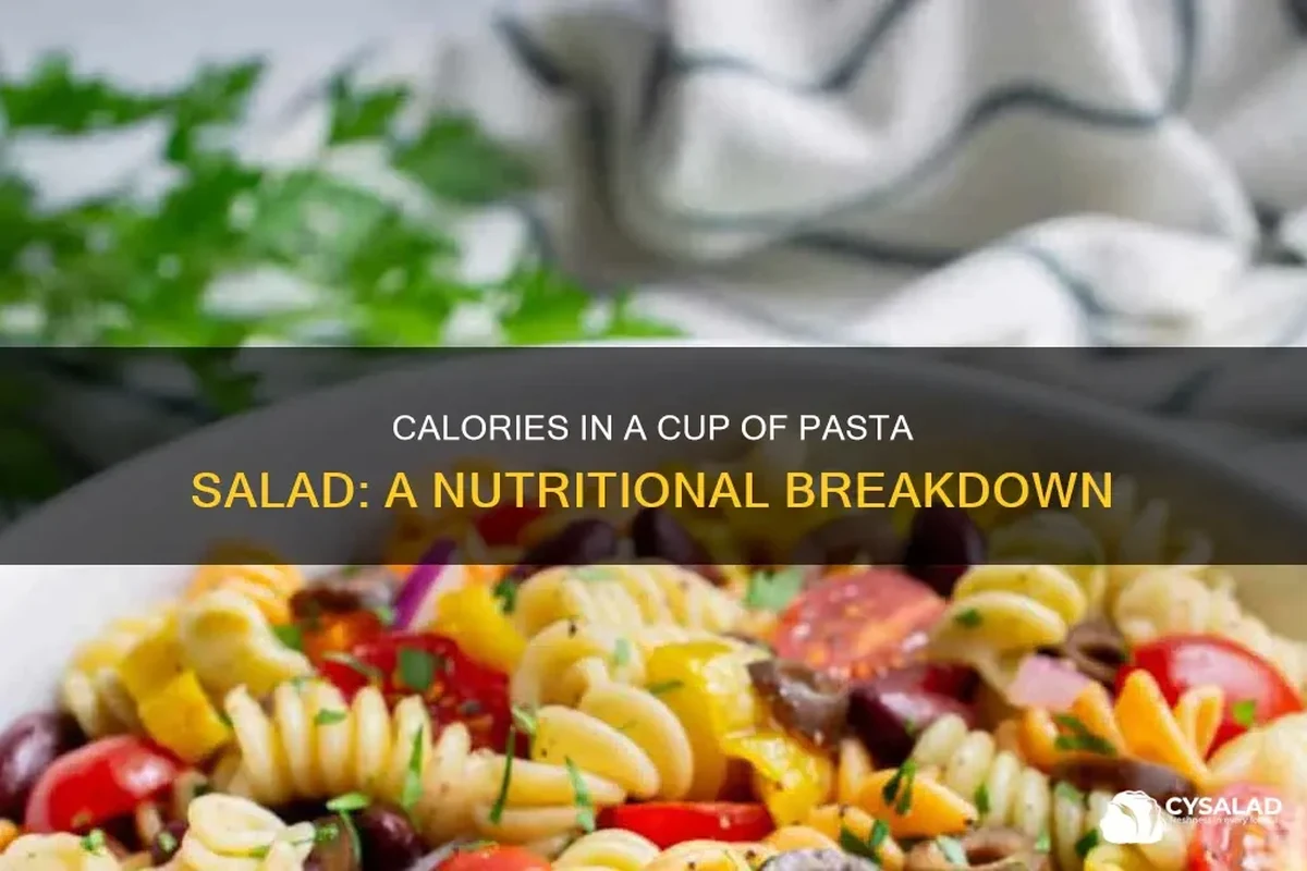 A bowl of pasta salad with vegetables, dressing, and a measuring cup beside it