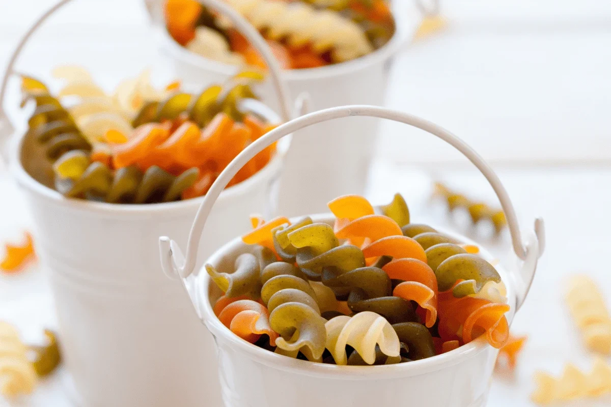 Measuring dry pasta in a cup beside a pot of cooked pasta in a home kitchen
