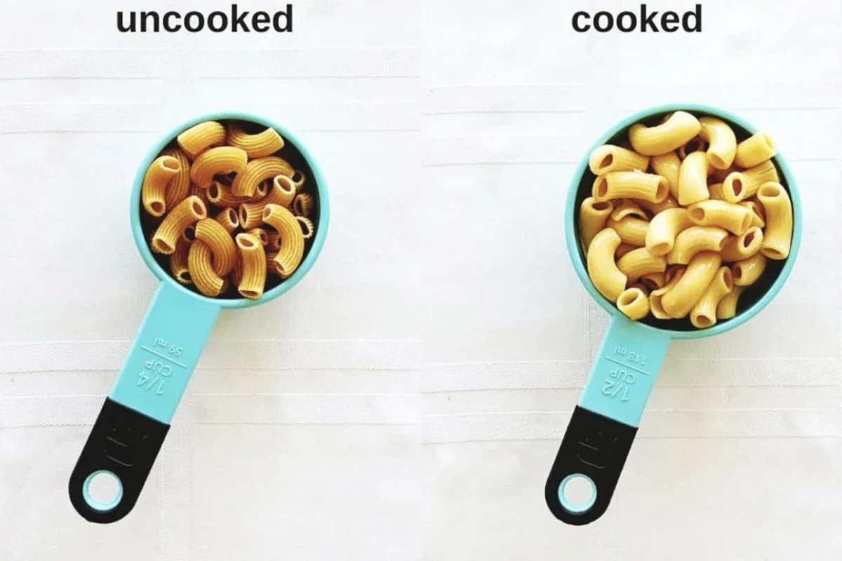 Dry pasta measured in a cup beside a kitchen scale in a bright home kitchen
