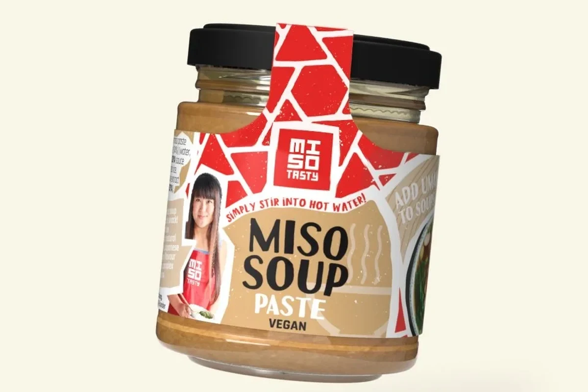 Miso paste being stirred into a cup of warm water in a small kitchen bowl