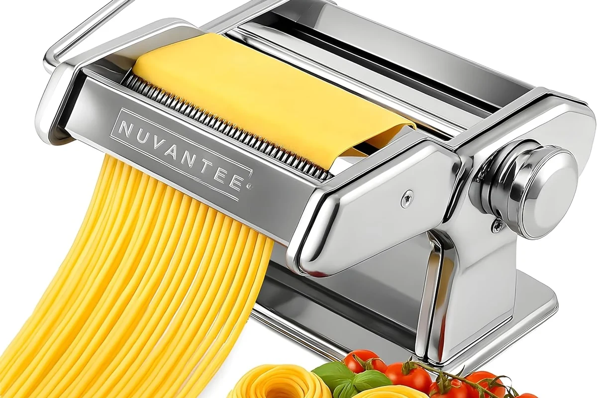 Fresh pasta dough being rolled through a manual pasta machine in a home kitchen