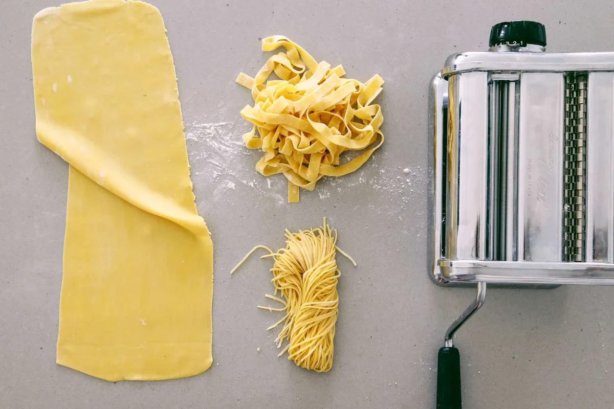 Fresh pasta dough being rolled and cut on a kitchen counter