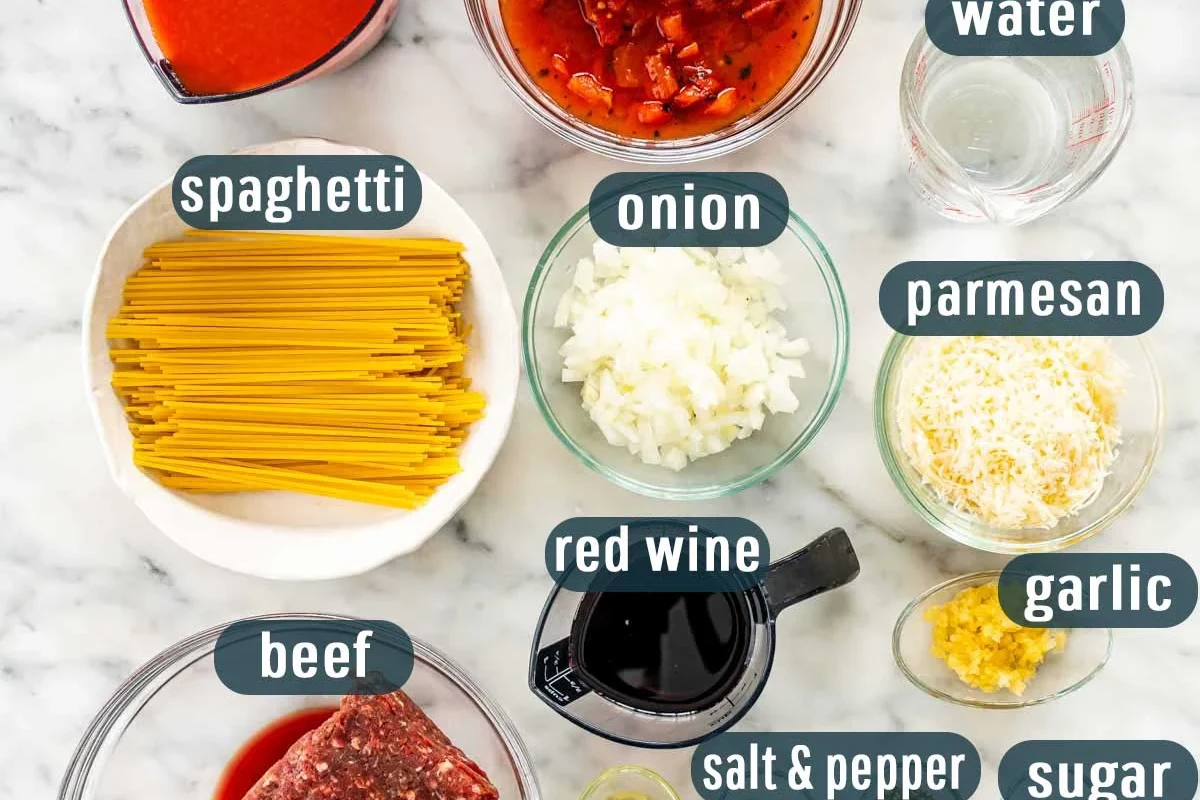 Ingredients for pasta dough with flour, eggs, water, and shaped noodles on a kitchen counter