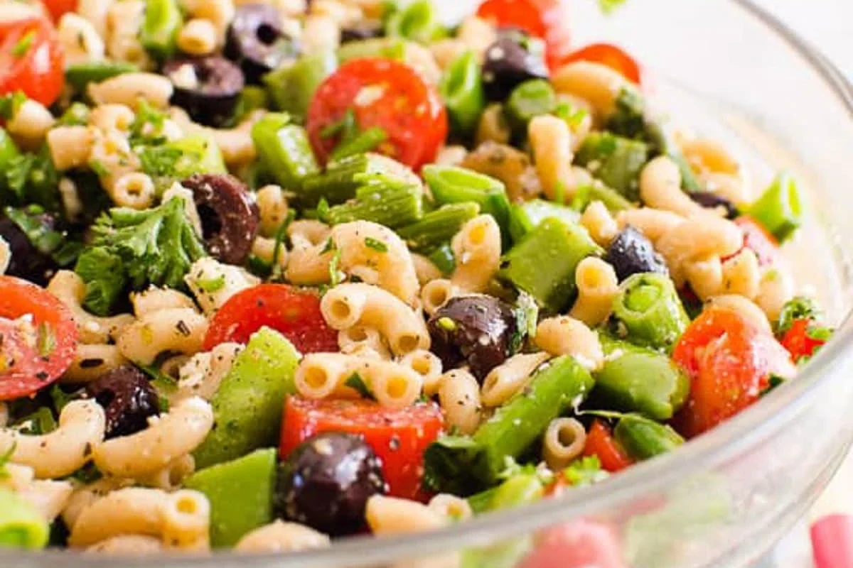 Healthy pasta salad bowl with vegetables, lean protein, and light dressing on a kitchen counter